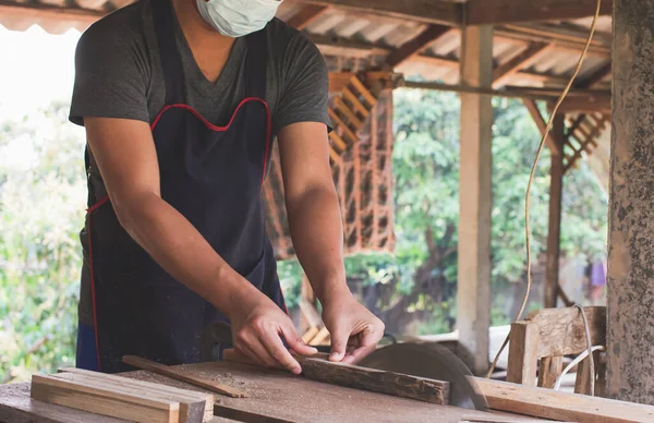 Asyalı marangoz fabrikasında bir masa masasının üzerine bir kutu yapmak için dairesel testere kullanıyor. Ev konseptinde kendi patronun olarak çalışıyorsun.