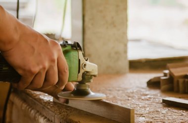 Asyalı marangoz fabrikasındaki tezgahın ahşap yüzeyini pürüzsüz hale getirmek için elektrikli odun zımpara makinesi kullanıyor. Küçük işletme, evde kendi patronun olarak çalışmak.