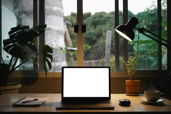 Laptop mockup, white screen for use, technology, social media, office equipment and notebooks, with work lamp, coffee cup and plant pots decorated green area, work corner on the desk.