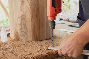 Bir marangoz çalışıyor. Küçük fabrikasında tahta kutuları delmek için elektrikli matkap kullanıyor..