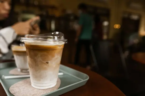 コーヒーショップのテーブルの上に置かれたプラスチック製のマグでコーヒーラテをアイスしました テキストのスペースをコピーする — ストック写真