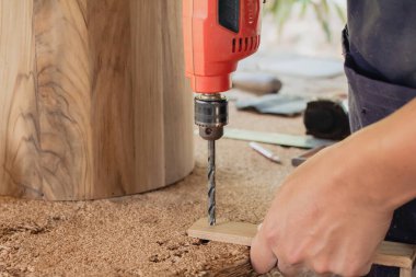 Bir marangoz çalışıyor. Küçük fabrikasında tahta kutuları delmek için elektrikli matkap kullanıyor..