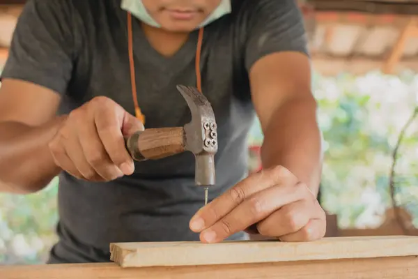 wood craftsman using a hammer hammering nails wood make product working at carpentry workshop  furniture project