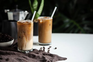 Bardağın üstünde kahve fincanı, kavrulmuş kahve ve ahşap masada İtalyan moka kahve demliği.