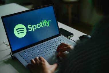 LAMPHUN, THAILAND - 15 Eylül 2023: Kadın bir dizüstü bilgisayar kullanıyor ve SPOTIFY müzik listesi logosunu ekranda arıyor. Spotify uluslararası alanda ünlüdür..