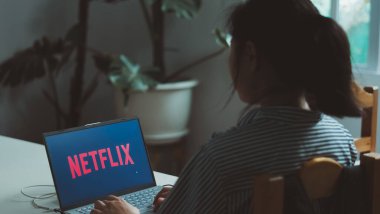 LAMPHUN, THAILAND - 15 Eylül 2023: Kadın dizüstü bilgisayar kullanıyor ve ekranda Netflix logosu seyrediyor. Netflix uluslararası alanda ünlüdür..