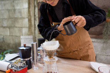İnsanlar kahve yapmak için bardağa sıcak kahve damlatıyor, ekipmanla, yavaş barda demlenen aletlerle.