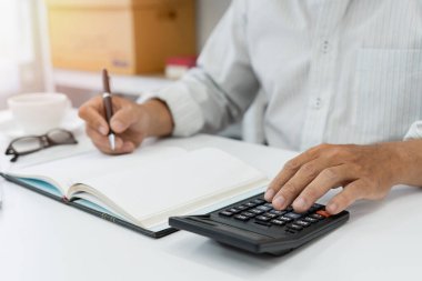 Bir hesap makinesi kullanarak kişisel gelir vergisini hesaplamaya odaklanan bu iş adamı, finansal planlamayı hassasiyetle ve adanmışlıkla inceliyor..