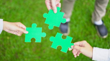İş dünyası liderleri, sürdürülebilir başarı için gerekli çevre, sosyal ve yönetim (ESG) stratejilerinin parçalarını birleştirerek, elde bulunan bir yapboz ile sembolize edilen yeşil ortaklık üzerinde işbirliği yaparlar..