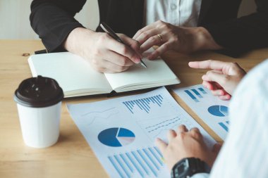 İş toplantısı, iş arkadaşları işbirliği yapıyor, tavsiye veriyor ve hisse senedi performansı konusunda danışmanlık yapıyor. Notlar alıyorlar ve grafikleri analiz ediyorlar, birlikte çalışıp sonuçları etkili bir şekilde gösteriyorlar..