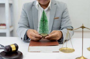 İş adamı bir çevre kampanyasına katılıyor, sembolik olarak bir ağaç tutuyor, sürdürülebilir geleceği desteklemek için doğanın korunmasını ve hukuki olarak korunmasını savunuyor.