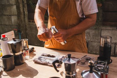 Adam öğütülmüş Arap fasulyelerinden taze bir bira hazırlıyor. Kırsal bir kafede elle paslanmaz çelik öğütücüye. Lezzetli ve aromatik bir kahve deneyimi.