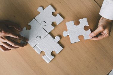 Başarılı iş ekibi, masa üzerindeki yapbozun son parçasını tamamlayarak, birlik, strateji ve ortak başarıyı temsil ederek, sorunları çözmek için işbirliği yapar..