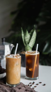 Bardağın üzerinde kahve fincanı, kavrulmuş fasulye kahvesi ve ahşap masada İtalyan moka kahve demliği. Dikey fotoğraf