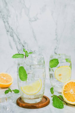 Berrak bir bardakta limonata, taze narenciye meyvesinden parlak sarı, serin ve canlı bir yaz içkisi deneyimi için stüdyoda çekilmiş..