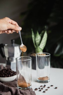 Evde kahve yapmak için kaşıkla hazır kahve dolduran bir el. Dikey fotoğraf