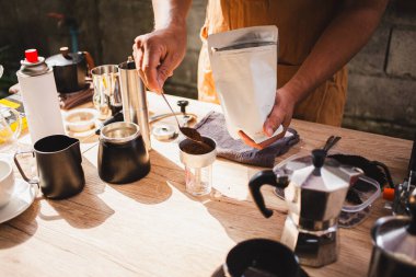  Barista taze öğütülmüş kahveyi taşınabilir öğütücüye boşaltıp ev yapımı biraya hazırlanıyor. Kavrulmuş fasulye kokusu havayı dolduruyor. Tutku duyarlılığını ve kahve kültürünü simgeliyor..