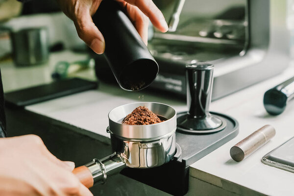 Freshly roasted coffee beans poured into a bucket bottomless of portafilter equipment coffee tools preparing for grinding and brewing. The perfect start to rich and flavorful coffee experience.	
