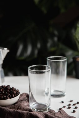 İki boş bardak ve bir beze konmuş kahve çekirdeği, Moka pot. Hazırlık ve kompozisyon dikey fotoğraf.