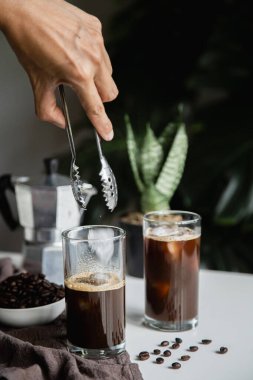 El 'in buzlu latte kahve yaparken buzlu fincana buz koyduğu hazır kahve. dikey resim