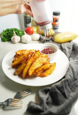 Hazırlık, fırında pişmiş patateslerin üzerine lezzetli kırmızı biber tozuyla sos sıkıştır. Ev yapımı mutfakta aşçı, ev yapımı. dikey resim