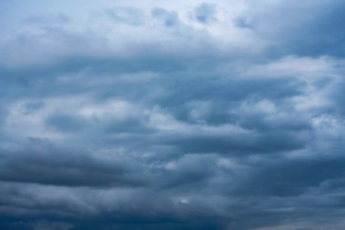 Yağmur mevsiminde mavi gökyüzü boyunca kara fırtına bulutları toplanıyor. Doğa, açık arazide yaklaşan fırtınanın sinyallerini verirken dramatik şekiller oluşturuyor..