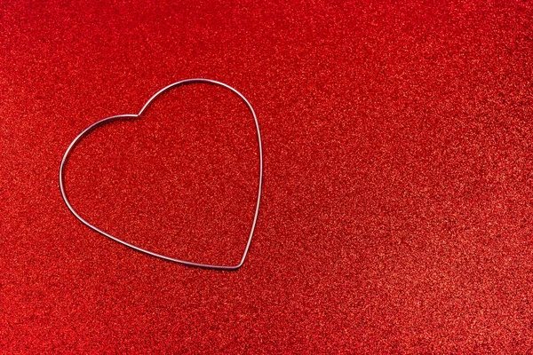 Valentines day background. Gold heart ring on a red glitter background.