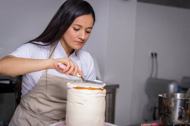 Pasta şefi pastayı krema ve böğürtlenle süslüyor.