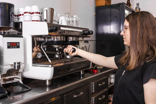 Spanish bar waitress preparing a coffee in the machine