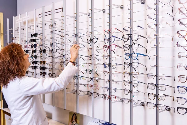 Stylish Optician Red Haired Optometrist Selecting Eyeglasses Wall Sized Display — Stock Photo, Image