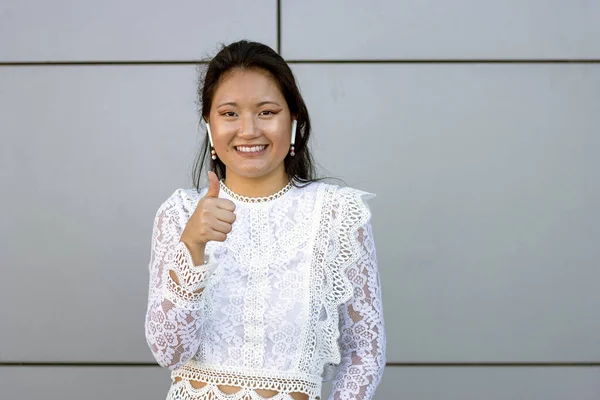 Miling Young Asian Tourist Med Trådløse Hodetelefoner Tomler Opp Gesture – stockfoto