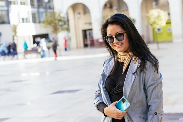 Улыбающаяся Азиатская Предпринимательница Солнечных Очках Держит Мобильный Телефон — стоковое фото