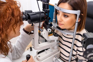 Optician and optometrist. Eye doctor and patient during an examination. clipart