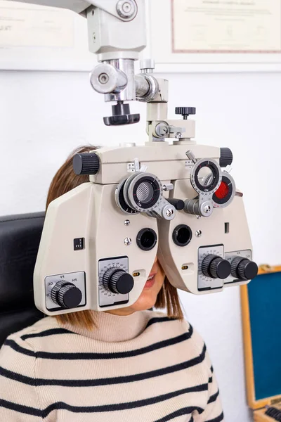 Optician and optometrist. Young woman during a visual test with phoropter.