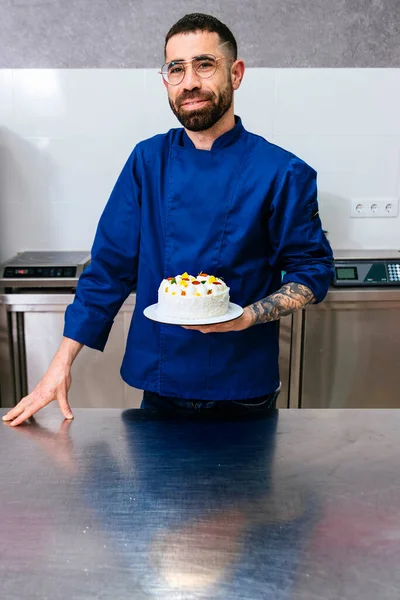 Pastry Chef. Male pastry chef presents his finished cake.