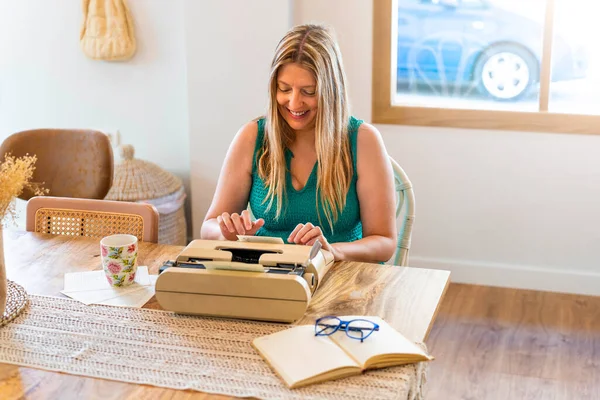 Blonde middle aged woman writes her next novel with an antique typewriter