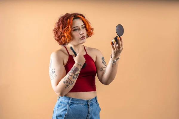Tattooed modern nonbinary redhead girl puts on makeup
