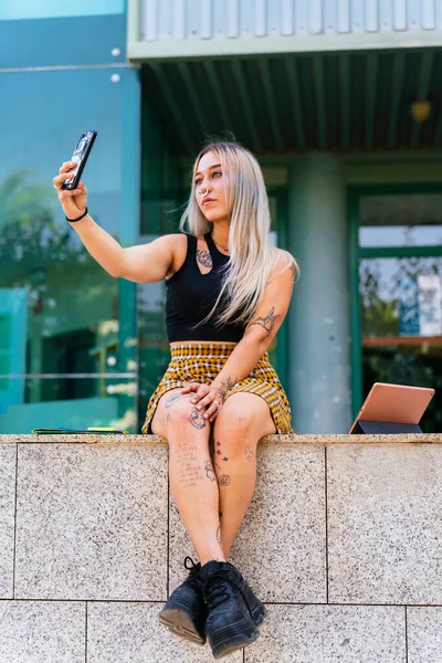 Back to School. Modern student with tattoos looking at herself on her phone.