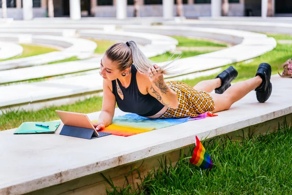 Back to School. Modern student with tattoos studies lying on an LGTBI flag