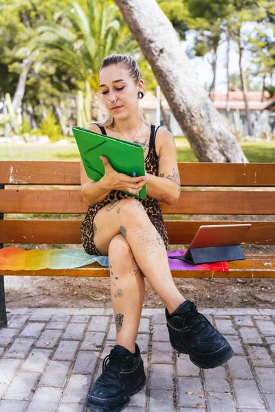 Back to School. Modern student with tattoos studies sitting on a bench on an LGTBI flag