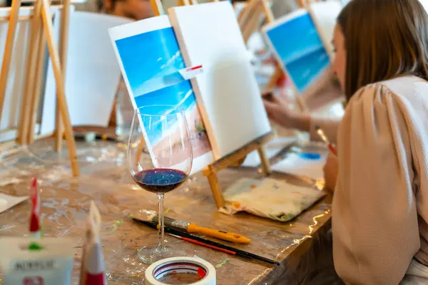 Sip and Paint Event. Painting with a glass of wine in hand