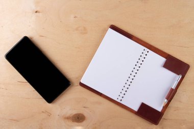 Dijitalleştirme kavramı. Kağıt defter akıllı telefona karşı. Boş siyah ekranlı ve boş cüzdanlı dijital telefon ahşap masanın üzerinde.