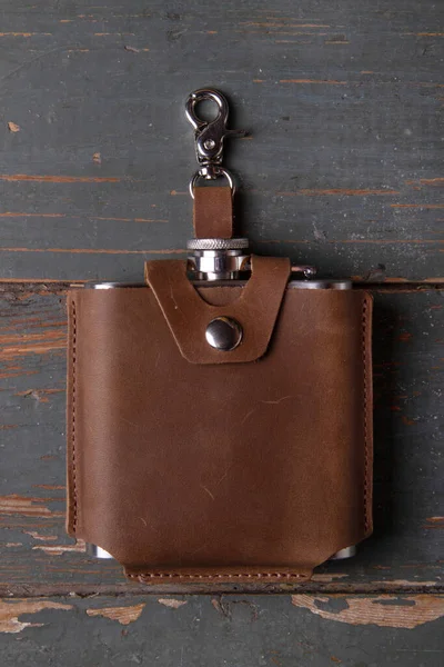 Hip flask in leather case on painted wooden timber