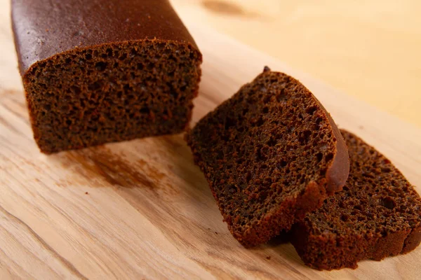 stock image Dark bread in loaf and sliced form placed on light beige wooden surface. selective focus