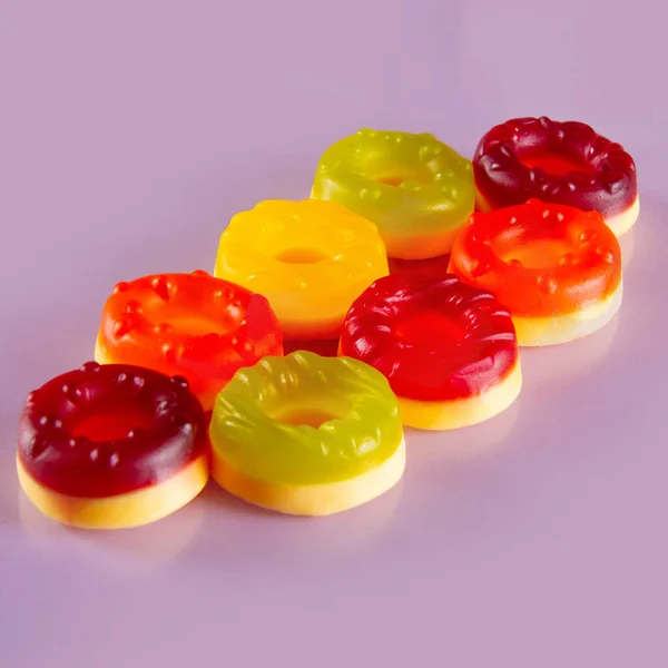 Osiem Okrągłych Cukierków Leży Fioletowym Tle Słodkie Okrągłe Rozkosze Kolorowym — Zdjęcie stockowe