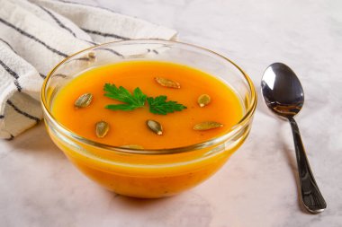 Balkabağı ve tatlı patatesle yapılmış vejetaryen sonbahar çorbası, hafif mermer arka planda düzenlenmiştir..