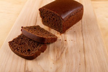 Koyu ekmek somunu ve dilimlenmiş muadili bej bej ahşap zemin üzerine güzelce yerleştirilmiş.