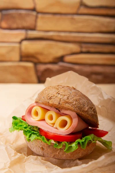 Vertical banner with brick wall background enhances the presence of ham and Swiss cheese sandwiches on whole wheat bread