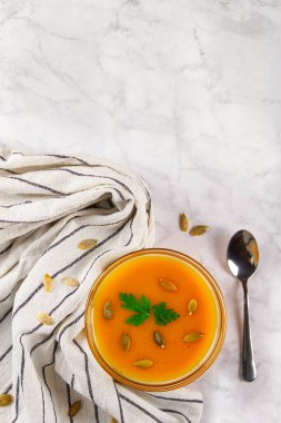 Bir kase lezzetli balkabağı kremalı çorba. Fotokopi alanı ile mermer zemin üzerine yerleştirilmiş tohumlar..