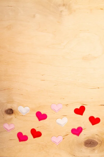 A lot of small hearts on wooden background with copy space. Greeting card with Love-filled emotions on rustic timber.